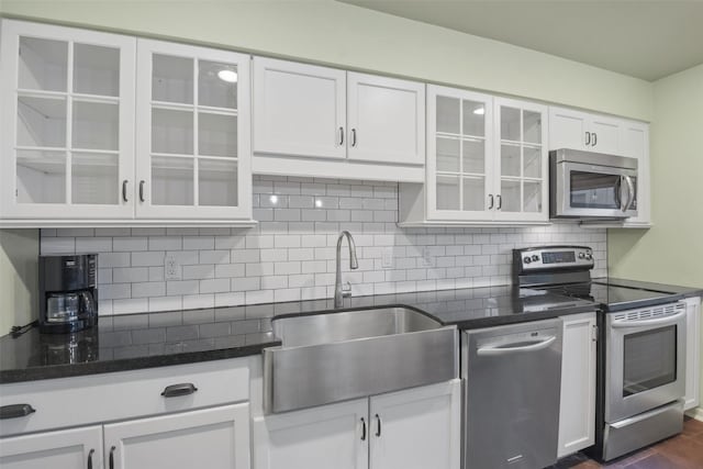 kitchen with sink, dark wood-type flooring, dark stone countertops, white cabinets, and appliances with stainless steel finishes