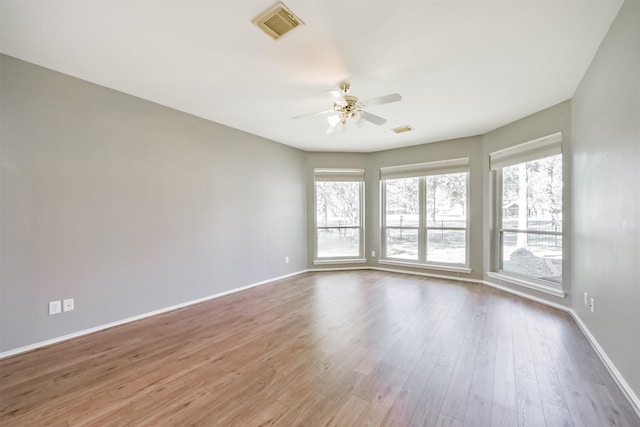 spare room with plenty of natural light, ceiling fan, and wood-type flooring