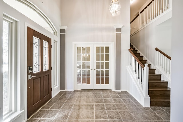 tiled entryway featuring a notable chandelier, a high ceiling, and french doors