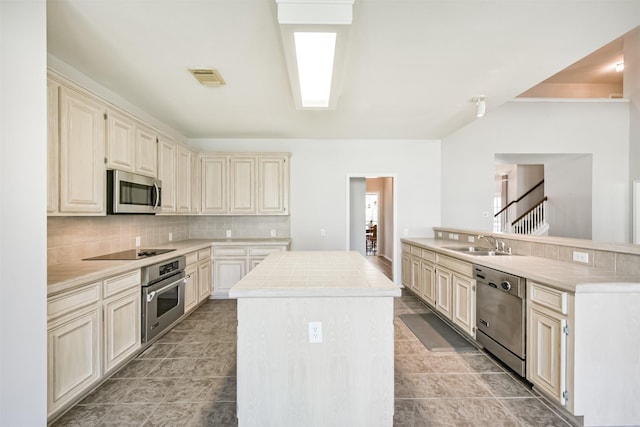 kitchen featuring a center island, backsplash, cream cabinets, sink, and appliances with stainless steel finishes