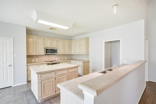 kitchen with tile countertops, backsplash, a kitchen island, and sink