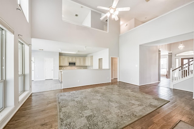 unfurnished living room featuring ceiling fan with notable chandelier, dark hardwood / wood-style flooring, and high vaulted ceiling