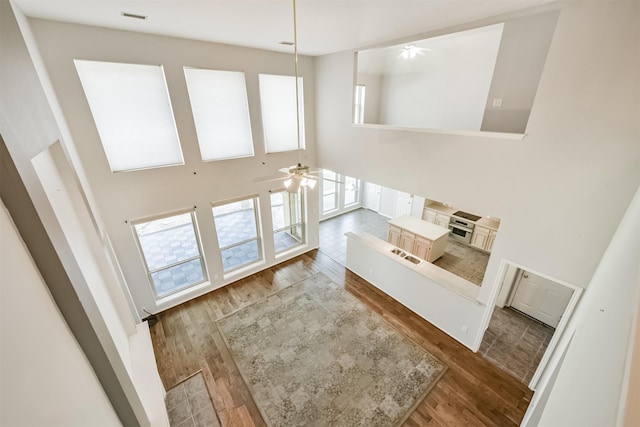 unfurnished living room featuring ceiling fan, hardwood / wood-style floors, and a high ceiling