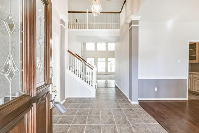 entrance foyer featuring ornate columns, hardwood / wood-style floors, a towering ceiling, and a notable chandelier