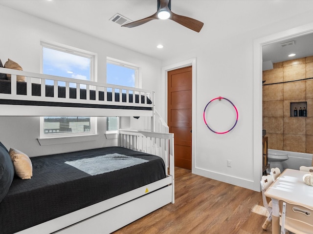 bedroom featuring hardwood / wood-style floors, ensuite bathroom, and ceiling fan