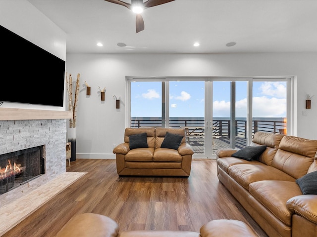 living room featuring a fireplace, wood-type flooring, a water view, and plenty of natural light