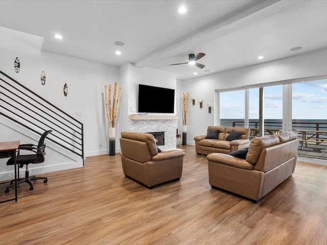 living room with a fireplace, light hardwood / wood-style flooring, and ceiling fan