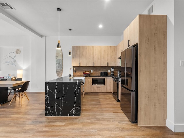 kitchen with light brown cabinets, light wood-type flooring, decorative light fixtures, and appliances with stainless steel finishes