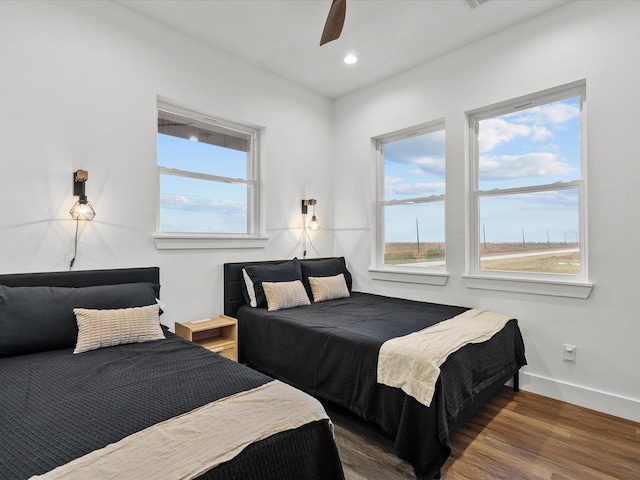 bedroom featuring multiple windows, ceiling fan, and dark hardwood / wood-style flooring