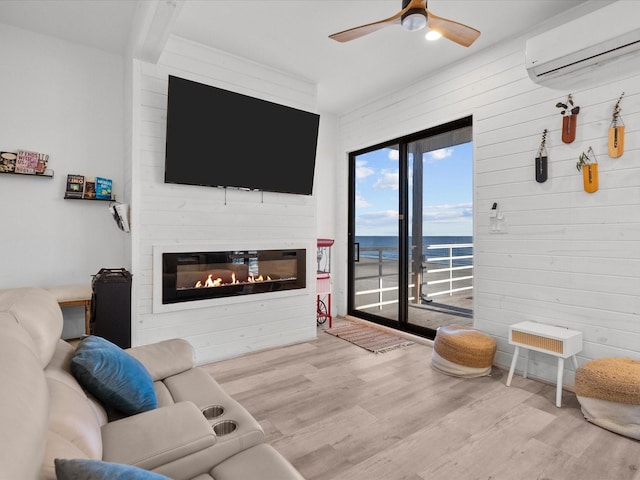 living room featuring a large fireplace, light hardwood / wood-style floors, an AC wall unit, and ceiling fan