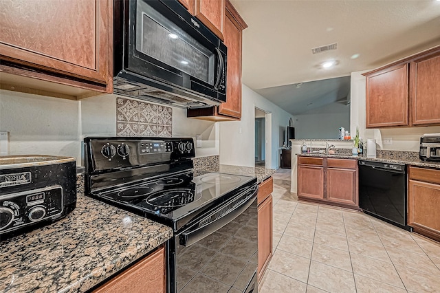 kitchen with sink, black appliances, light tile patterned floors, dark stone countertops, and lofted ceiling