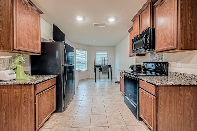 kitchen with stone counters, light tile patterned floors, and black appliances