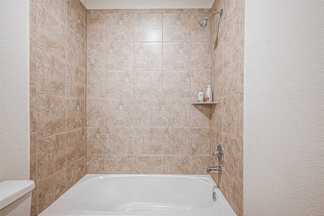 bathroom featuring tiled shower / bath combo and toilet