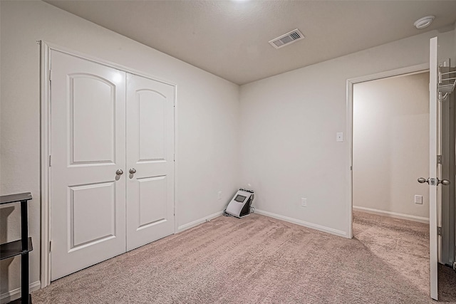 unfurnished bedroom with light carpet and a closet