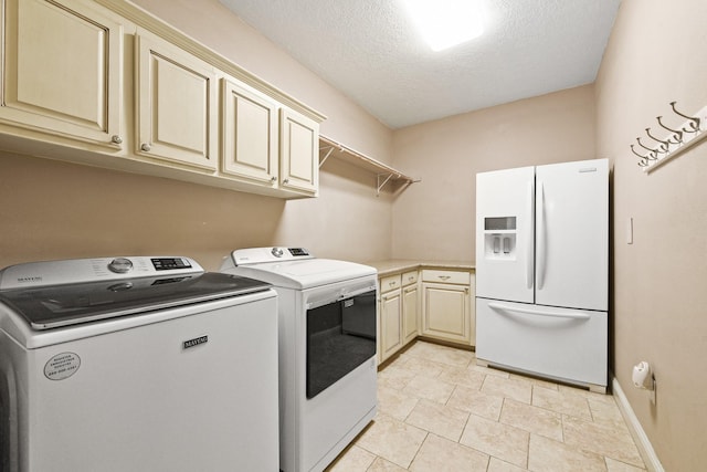 laundry area with washing machine and clothes dryer, cabinets, and a textured ceiling