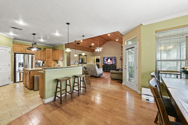 kitchen featuring a kitchen breakfast bar, stainless steel fridge, light hardwood / wood-style floors, a textured ceiling, and decorative light fixtures