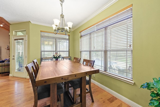 dining space with crown molding, an inviting chandelier, and light wood-type flooring