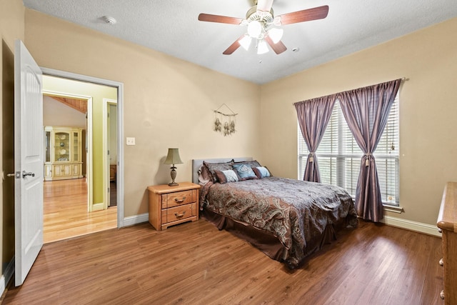 bedroom featuring a textured ceiling, ceiling fan, and dark wood-type flooring