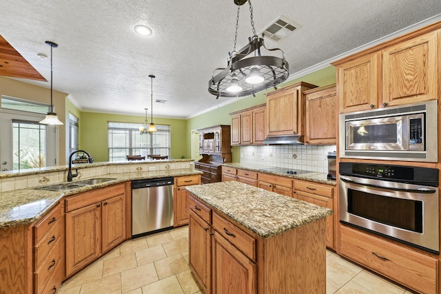 kitchen featuring ornamental molding, a center island, pendant lighting, and appliances with stainless steel finishes