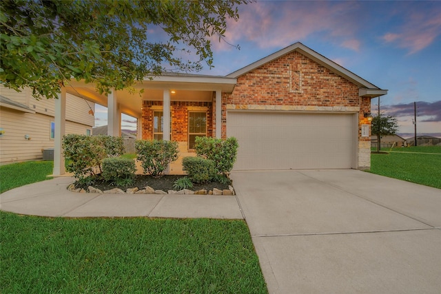 view of front of house featuring covered porch, a yard, a garage, and central AC unit