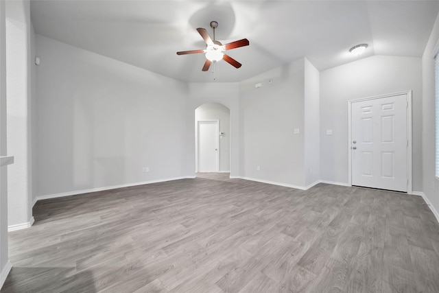 empty room with ceiling fan, lofted ceiling, and light wood-type flooring