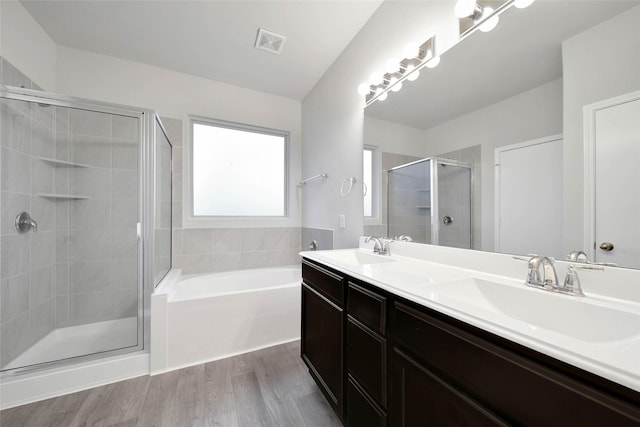 bathroom with plus walk in shower, hardwood / wood-style floors, and vanity