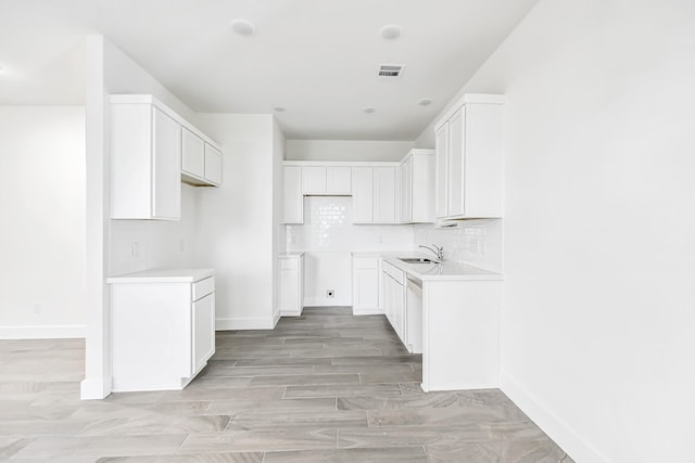 kitchen featuring white cabinets, decorative backsplash, sink, and light hardwood / wood-style flooring