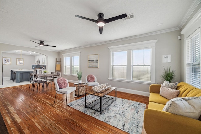 living room with ceiling fan, hardwood / wood-style floors, a textured ceiling, and ornamental molding