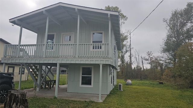 rear view of property featuring a lawn, a patio, and a wooden deck