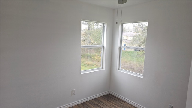 empty room with dark hardwood / wood-style flooring and a healthy amount of sunlight