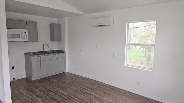 kitchen with gray cabinetry, sink, a wall mounted air conditioner, and dark wood-type flooring