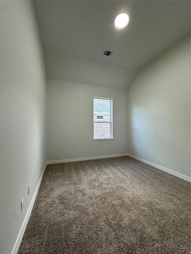 spare room featuring carpet floors and vaulted ceiling