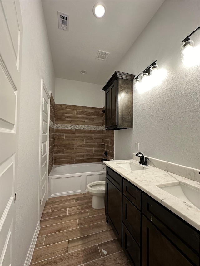 full bathroom with hardwood / wood-style floors, vanity, tiled shower / bath combo, and toilet