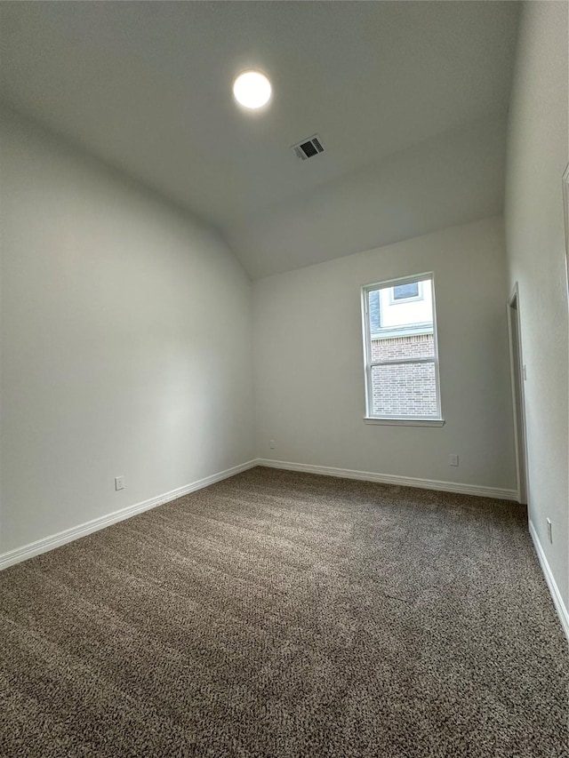 empty room featuring carpet and vaulted ceiling