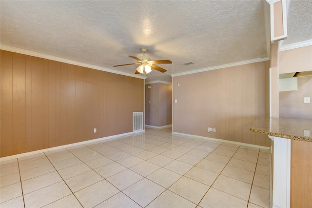 tiled empty room featuring ceiling fan, ornamental molding, a textured ceiling, and wooden walls