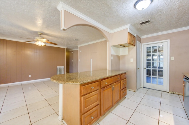 kitchen featuring ceiling fan, wood walls, ornamental molding, and light tile patterned floors