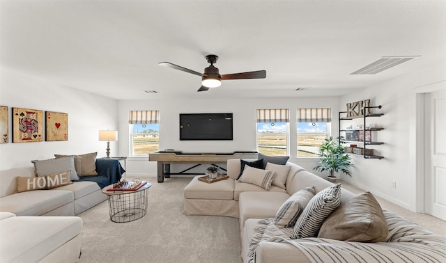 living room with ceiling fan, visible vents, baseboards, and light colored carpet