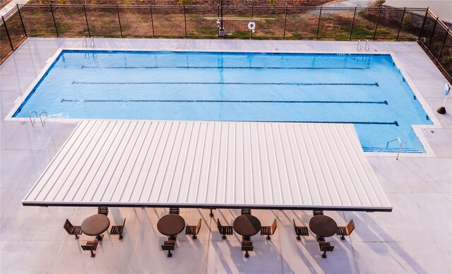 community pool with fence and a patio