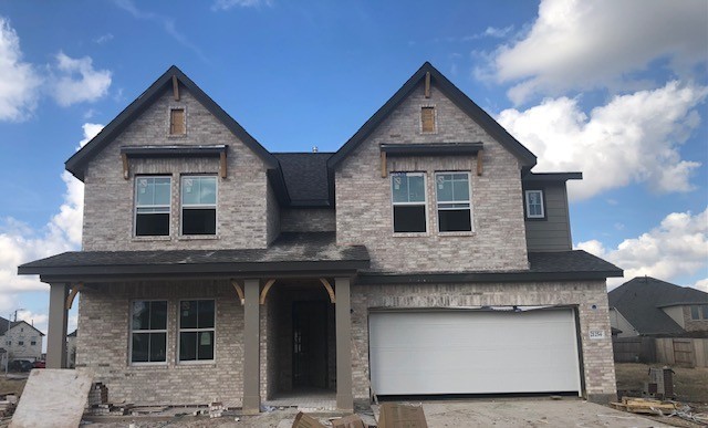 view of front of house with covered porch, brick siding, and an attached garage