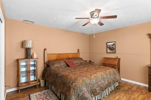 bedroom featuring ceiling fan, dark wood-type flooring, and a textured ceiling