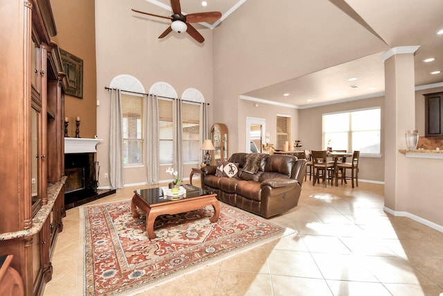 tiled living room with a high ceiling, ceiling fan, and ornamental molding