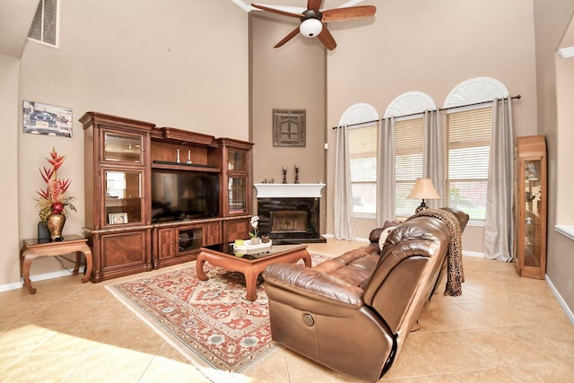 living room featuring ceiling fan, light tile patterned floors, and a high ceiling