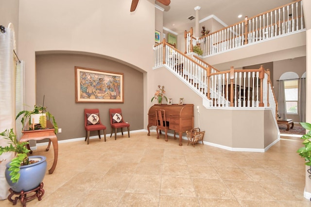 tiled entryway featuring ceiling fan and a towering ceiling