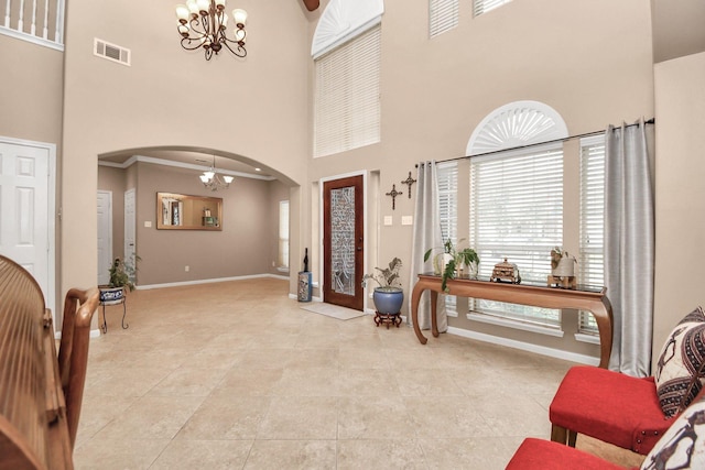 foyer entrance with crown molding, light tile patterned floors, a high ceiling, and a notable chandelier