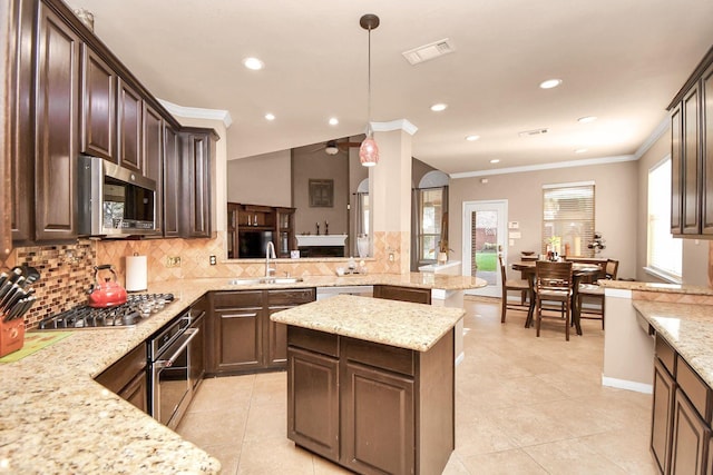 kitchen with backsplash, sink, appliances with stainless steel finishes, decorative light fixtures, and kitchen peninsula