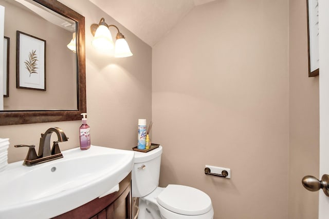 bathroom featuring vanity, lofted ceiling, and toilet