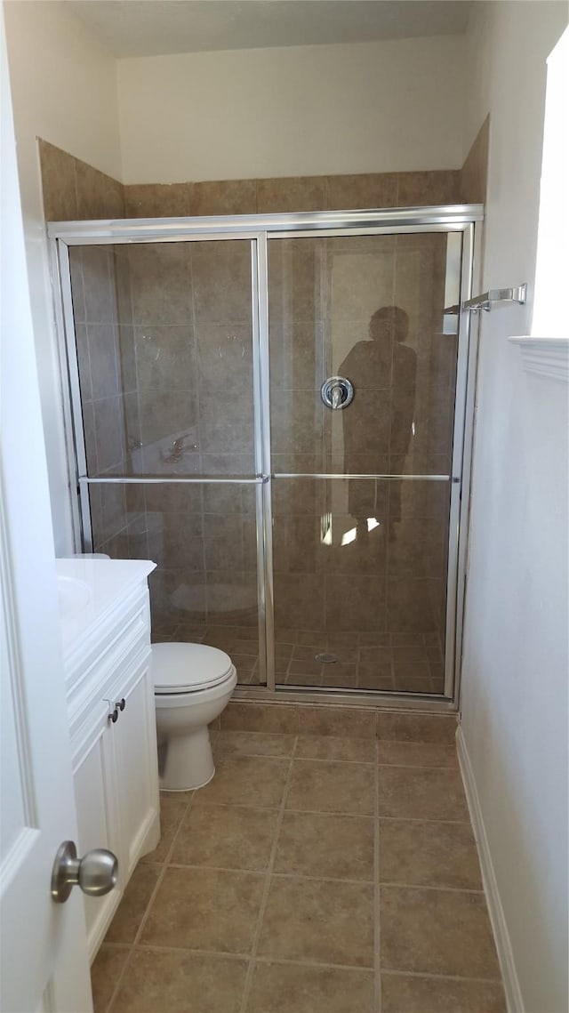 bathroom with tile patterned floors, vanity, toilet, and walk in shower