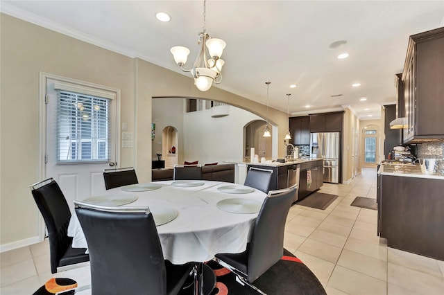 tiled dining area with a notable chandelier, ornamental molding, and sink