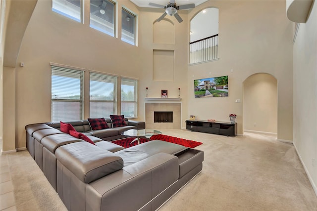 living room with carpet, plenty of natural light, a towering ceiling, and a tile fireplace