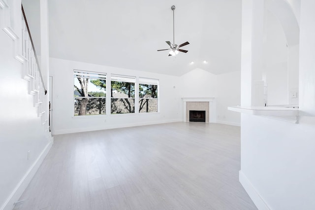 unfurnished living room featuring ceiling fan, light wood-type flooring, high vaulted ceiling, and a tiled fireplace